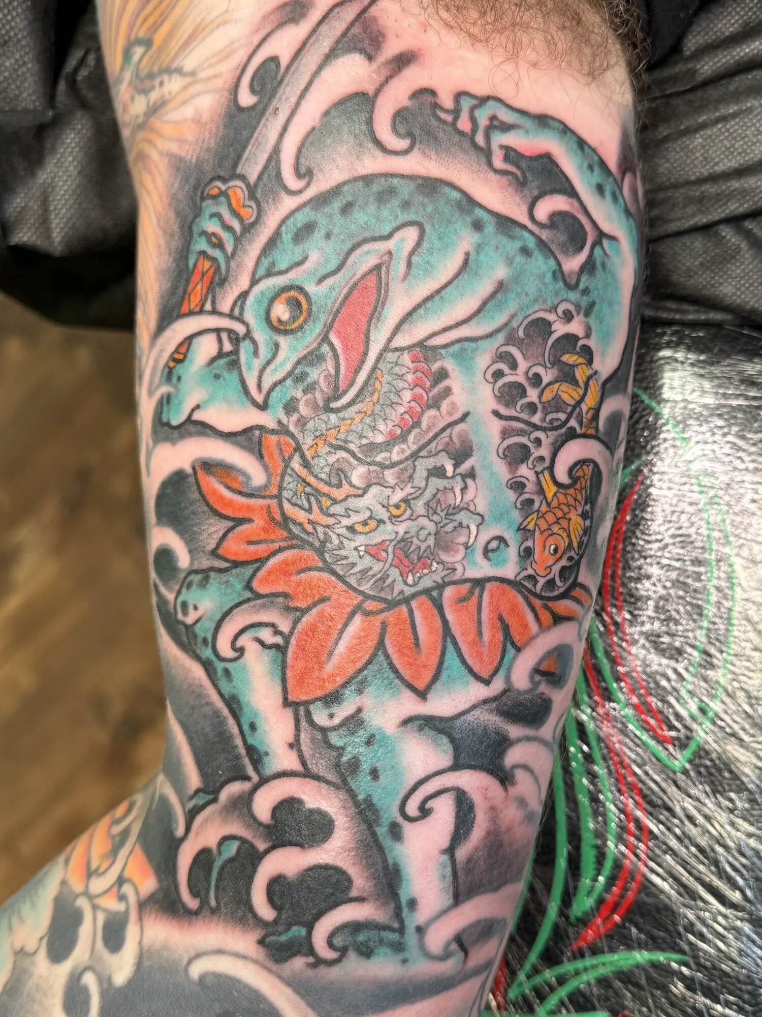 Japanese dragon and lotus arm tattoo in green, red and grey by Josh Robinson in Dallas, TX