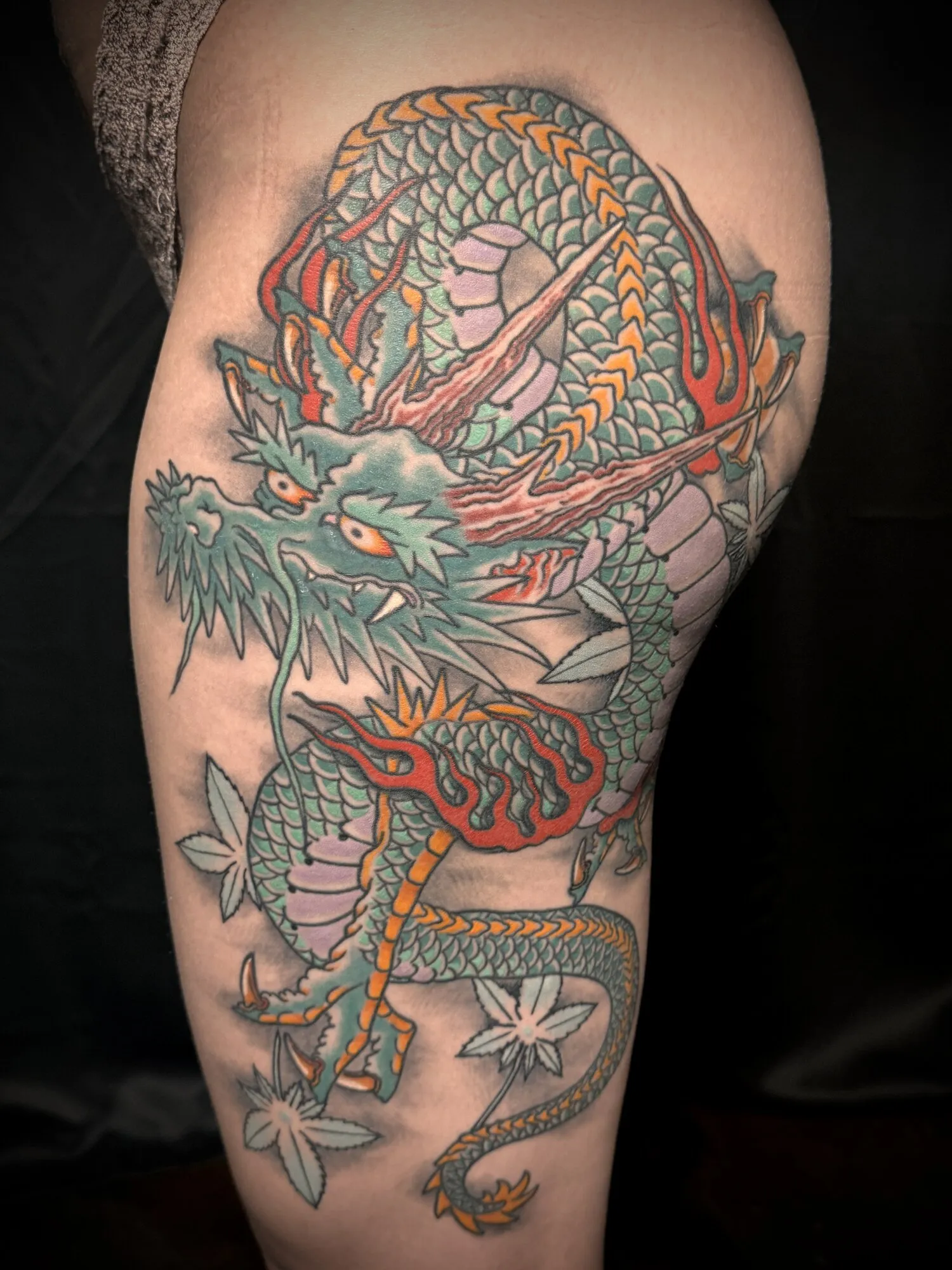 Japanese dragon thigh tattoo in green and orange by Josh Robinson in Dallas, TX