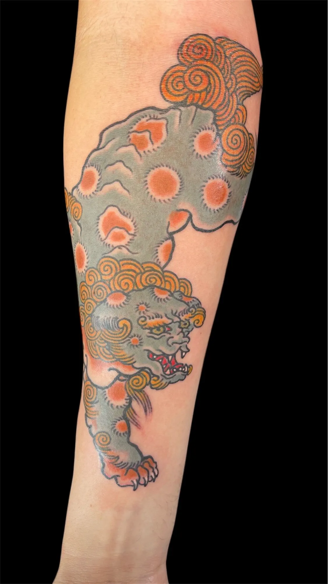 Japanese foo dog and clouds forearm tattoo in grey and orange by Josh Robinson in Dallas, TX
